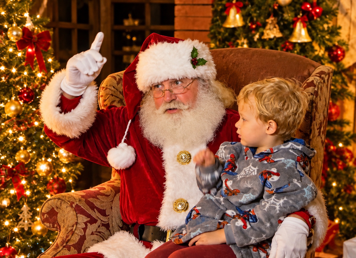Santa sharing a Christmas story with a young guest beside decorated trees