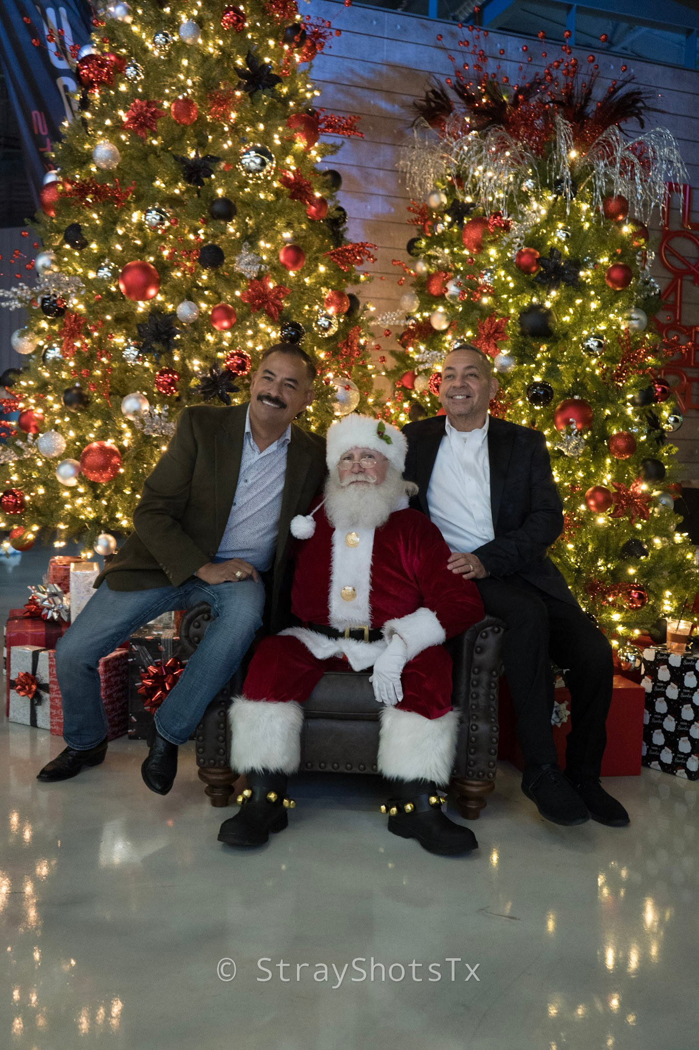 San Antonio Santa welcoming guests beside decorated Christmas trees